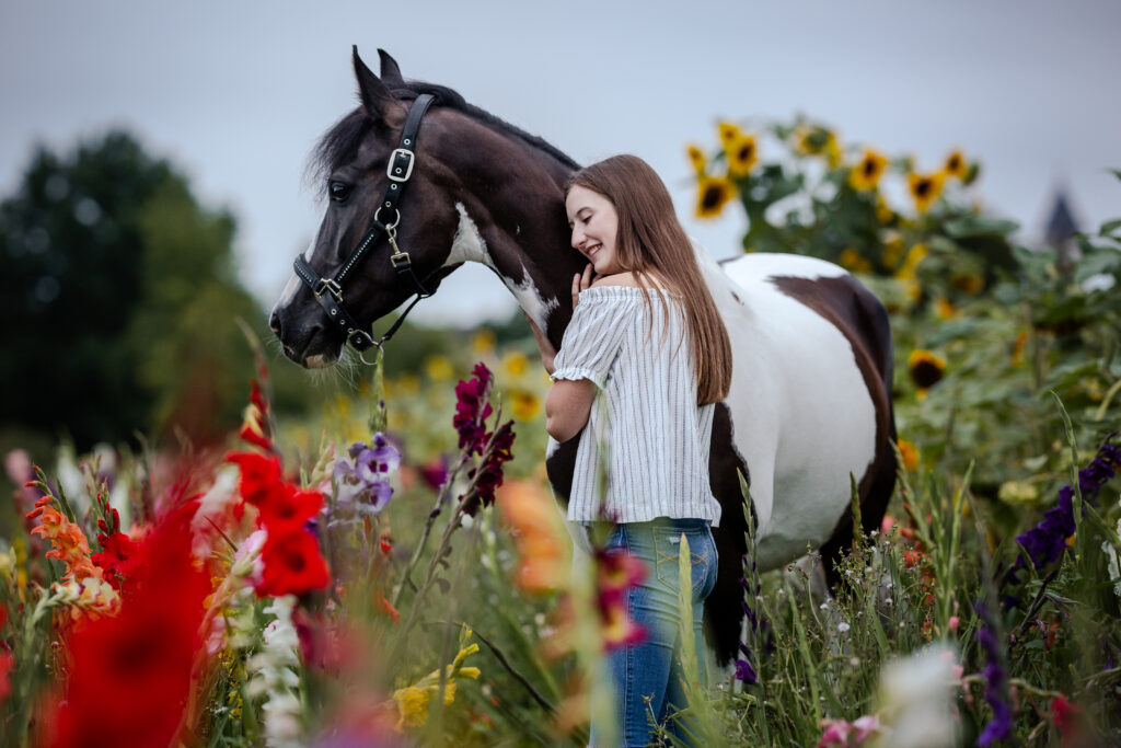 Frau kuschelt Pferd bei Fotoshooting im Blumenfeld mit Coralie Duda Fotografie im Wetteraukreis