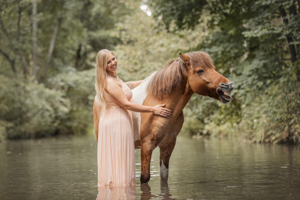 Frau mit gähnendem Pony im Wasser bei Fotoshooting mit Coralie Duda Fotografie im Wetteraukreis