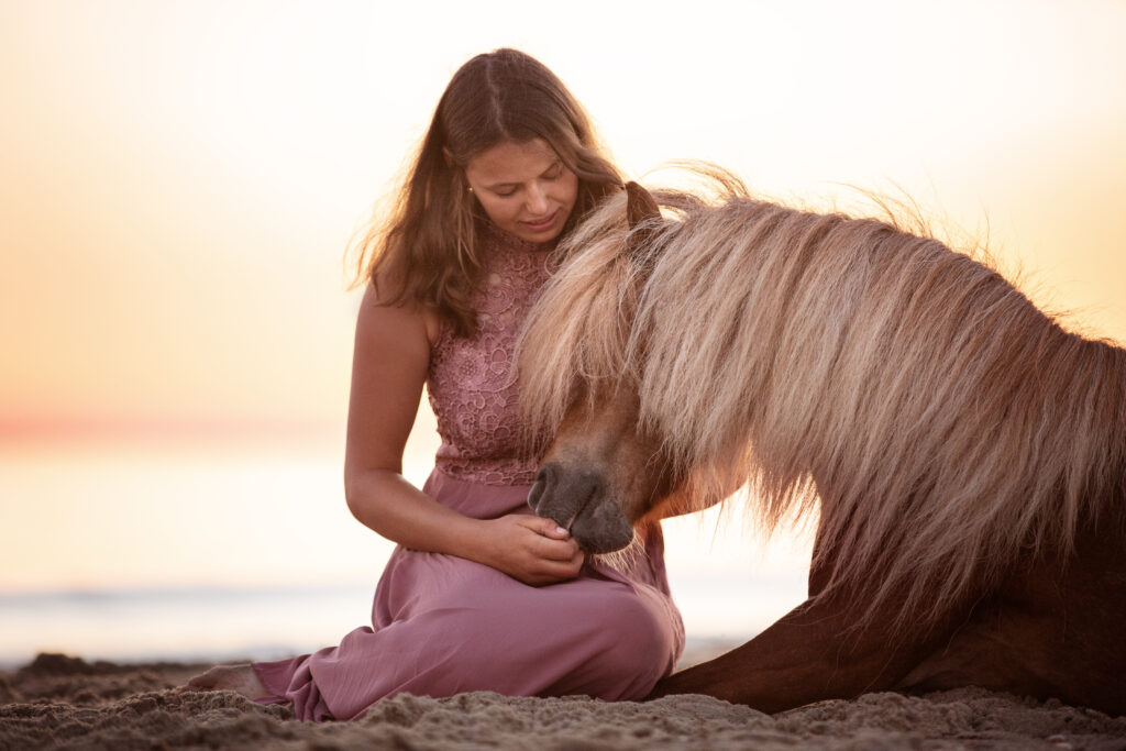 Frau mit Pony liegend im Sand bei Fotoshooting am Strand mit Coralie Duda Fotografie in Renesse