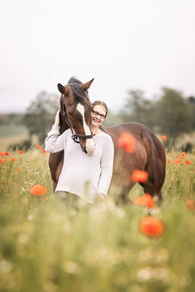 Frau kuschelt Pferd im Mohnblumenfeld bei Fotoshooting mit Coralie Duda Fotografie im Main-Kinzig-Kreis